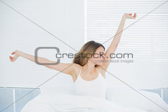 Lovely woman stretching out sitting on her bed