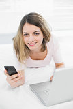 Cute smiling woman holding her smartphone looking at camera