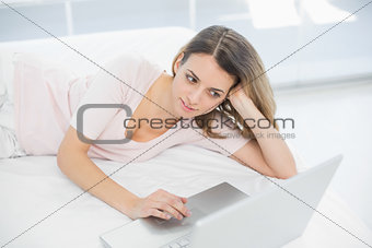 Woman using her notebook while lying on her bed
