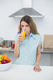 Serious young woman drinking a glass of orange juice