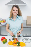 Sweet smiling woman cutting vegetables standing in kitchen