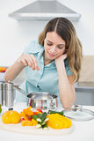 Content brunette woman cooking with vegetables standing in kitchen