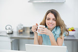 Cheerful smiling woman holding a cup posing in her kitchen