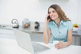 Pretty smiling woman sitting in her kitchen while holding a cup