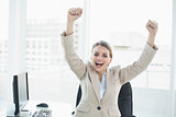 Happy cheering woman raising her arms sitting on her swivel chair