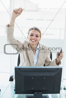 Content blonde businesswoman cheering sitting on her swivel chair