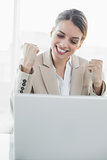 Content young businesswoman cheering sitting at her desk