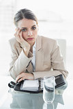 Attractive bored businesswoman looking at camera while sitting at her desk