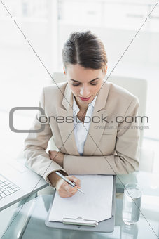 Young concentrated businesswoman writing on a clipboard