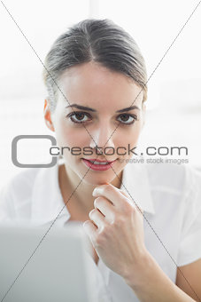 Content thinking businesswoman smiling softly at camera