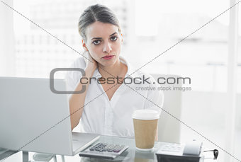 Calm serious businesswoman sitting at her desk