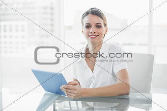 Gleeful smiling businesswoman working with her tablet looking at camera