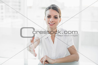 Polite young businesswoman reaching her hand to camera