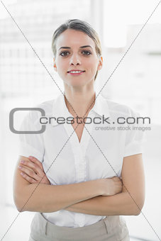 Attractive businesswoman posing with arms crossed looking at camera