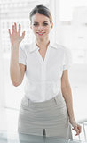 Beautiful businesswoman waving standing in her office