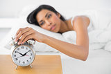 Attractive tired woman turning off the alarm clock