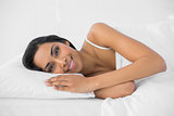 Calm smiling woman lying relaxing in her bed smiling at camera