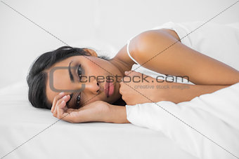 Tired lovely woman lying under the cover on her bed