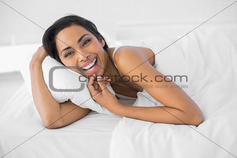 Content laughing woman lying under the cover on her bed