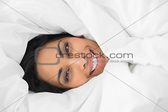 Happy calm woman lying under cover on her bed