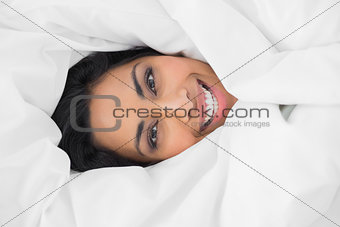 Content beautiful woman lying under cover on her bed