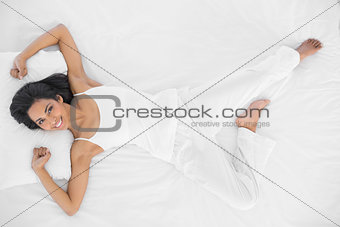 Gorgeous calm woman stretching out lying on her bed smiling at camera