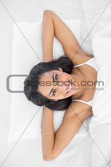 Content young woman lying on her bed smiling at camera