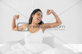 Lovely young woman sitting on her bed while stretching out