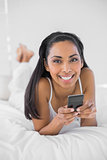 Beautiful smiling woman holding her smartphone smiling at camera