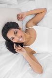 Attractive relaxing woman phoning while lying on her bed