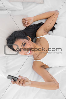 Lovely natural woman holding her smartphone smiling at camera