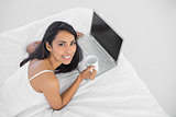 Content natural woman holding a cup lying on her bed