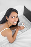 Beautiful relaxing woman holding a cup lying on bed