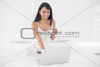 Gleeful natural woman home shopping with her notebook