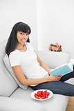 Beautiful relaxing woman holding a book sitting on a couch
