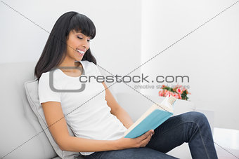 Lovely calm woman reading a book sitting on couch