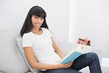 Beautiful calm woman holding a book while sitting on couch