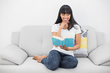 Peaceful content woman reading a book sitting on couch
