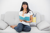 Beautiful smiling woman sitting on couch holding a book