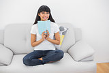 Attractive young woman holding a book smiling at camera