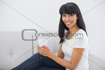 Relaxing young woman holding a cup sitting in bright living room