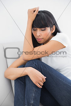 Thoughtful casual woman sitting on couch