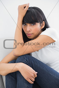 Beautiful thinking woman sitting on couch in bright living room