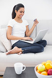 Smiling young woman home shopping with her laptop