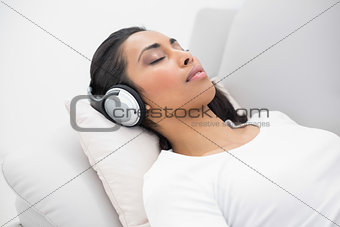 Calm woman listening to music lying on couch