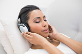 Enjoying natural woman listening to music lying on couch