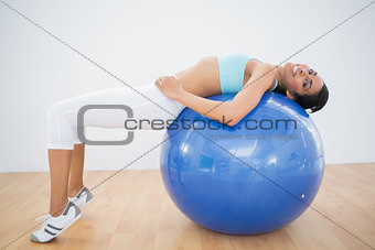 Cute sporty woman stretching on fitness ball