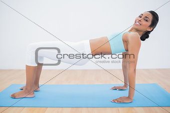 Content sporty woman doing yoga pose on exercise mat