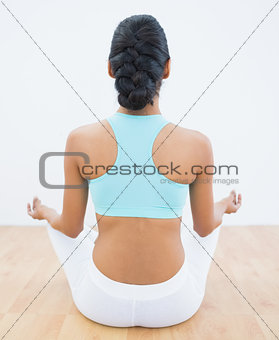 Rear view of slender calm woman meditating in lotus position
