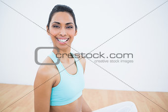 Cheerful sporty woman sitting in lotus position on floor